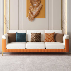 Modern white and orange sofa with patterned cushions against a neutral wall with abstract art.