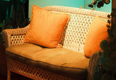 Vintage cane settee with orange cushions