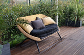 Solace curved rattan loveseat with charcoal cushions on a wooden deck